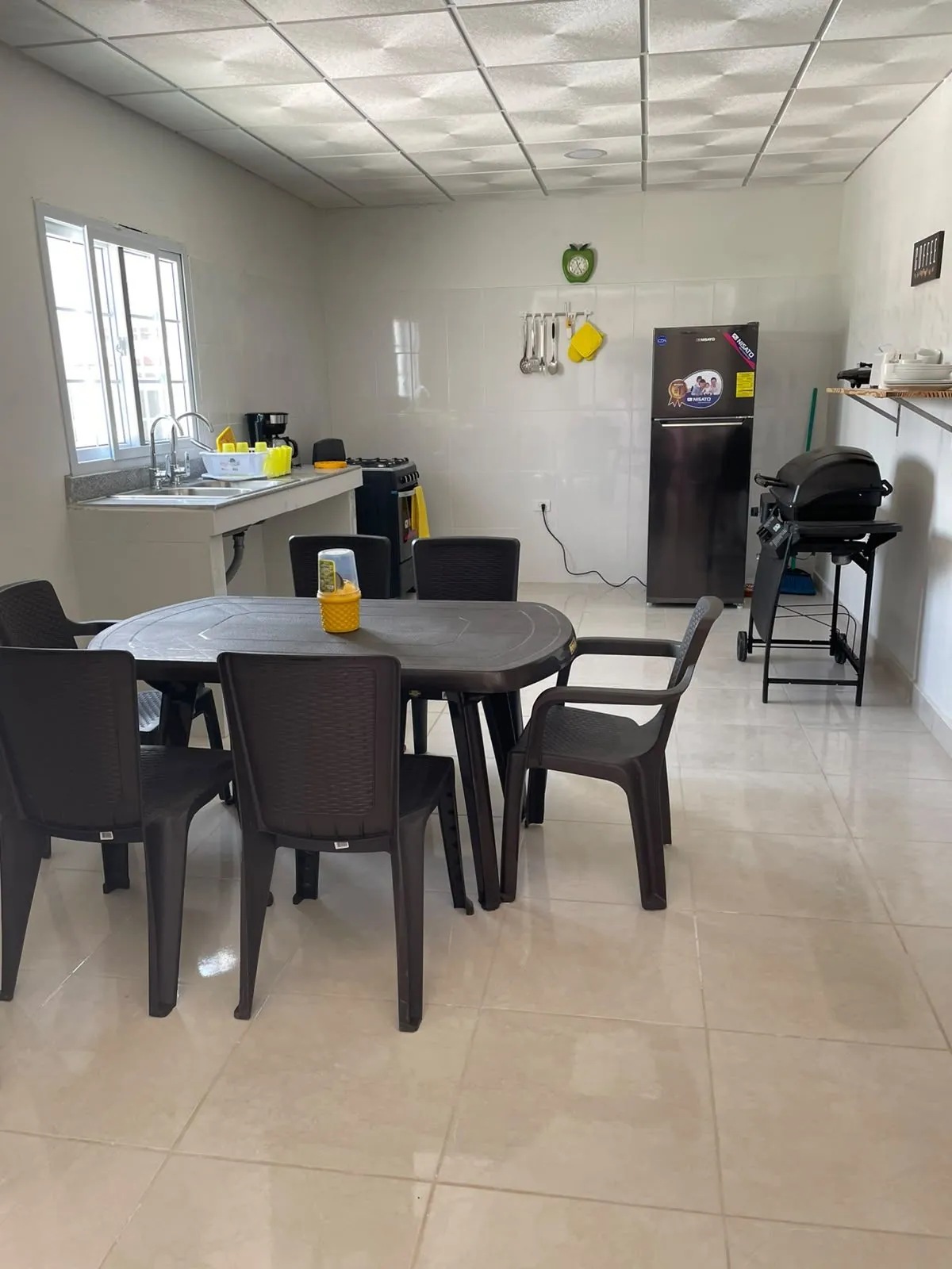 Cocina equipada con estufa, nevera y mesa de comedor para seis personas.