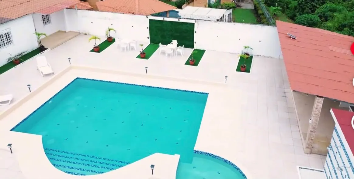 Piscina de adultos rectangular con escalones de mosaico azul y piscina para niños circular anexa.